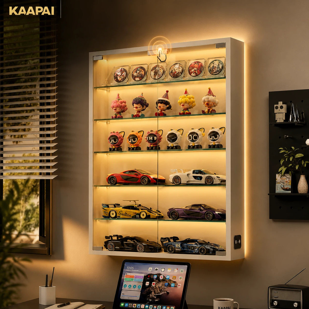 A KAAPAI illuminated glass display cabinet mounted on a wall, showcasing collectible figurines, sports cars, and model vehicles on glass shelves with warm LED lighting.