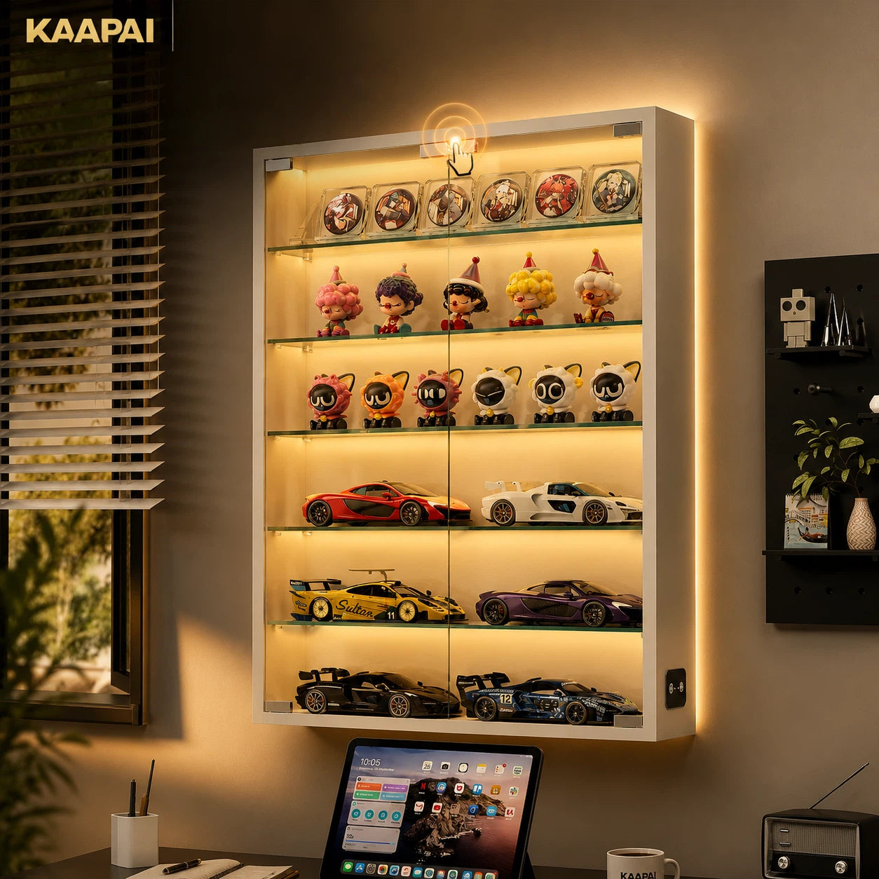 A KAAPAI illuminated glass display cabinet mounted on a wall, showcasing collectible figurines, sports cars, and model vehicles on glass shelves with warm LED lighting.
