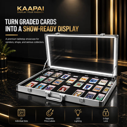 An open KAAPAI aluminum display case with a clear lid and built-in LED lighting, shown on a dark marble surface with cards arranged inside. Text on the image highlights 21 individual slots, price labels, LED lighting, and a 3-digit lock.